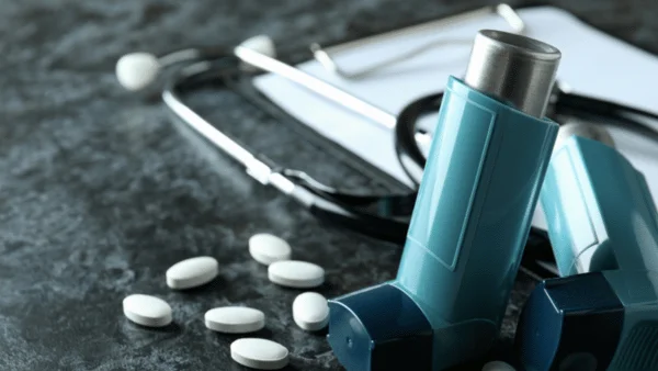 A blue asthma inhaler, some asthma pills and a stethoscope