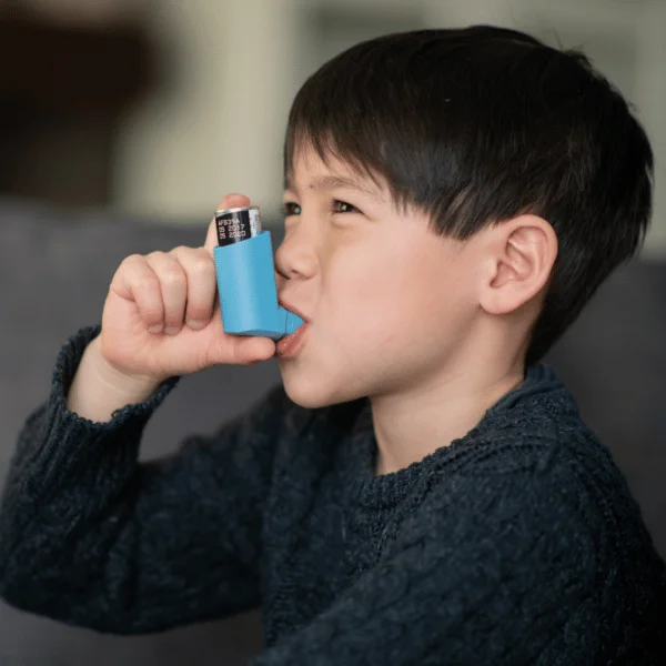 Small boy using asthma inhaler