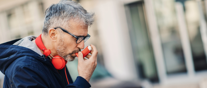 Man taking asthma inhaler in urban area